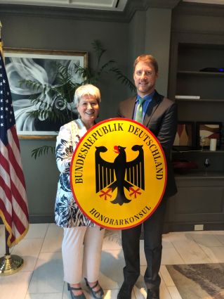 Norma Henning and Roland Chase standing with shield of German Honorary Consul in Tampa Honorarkonsul Florida